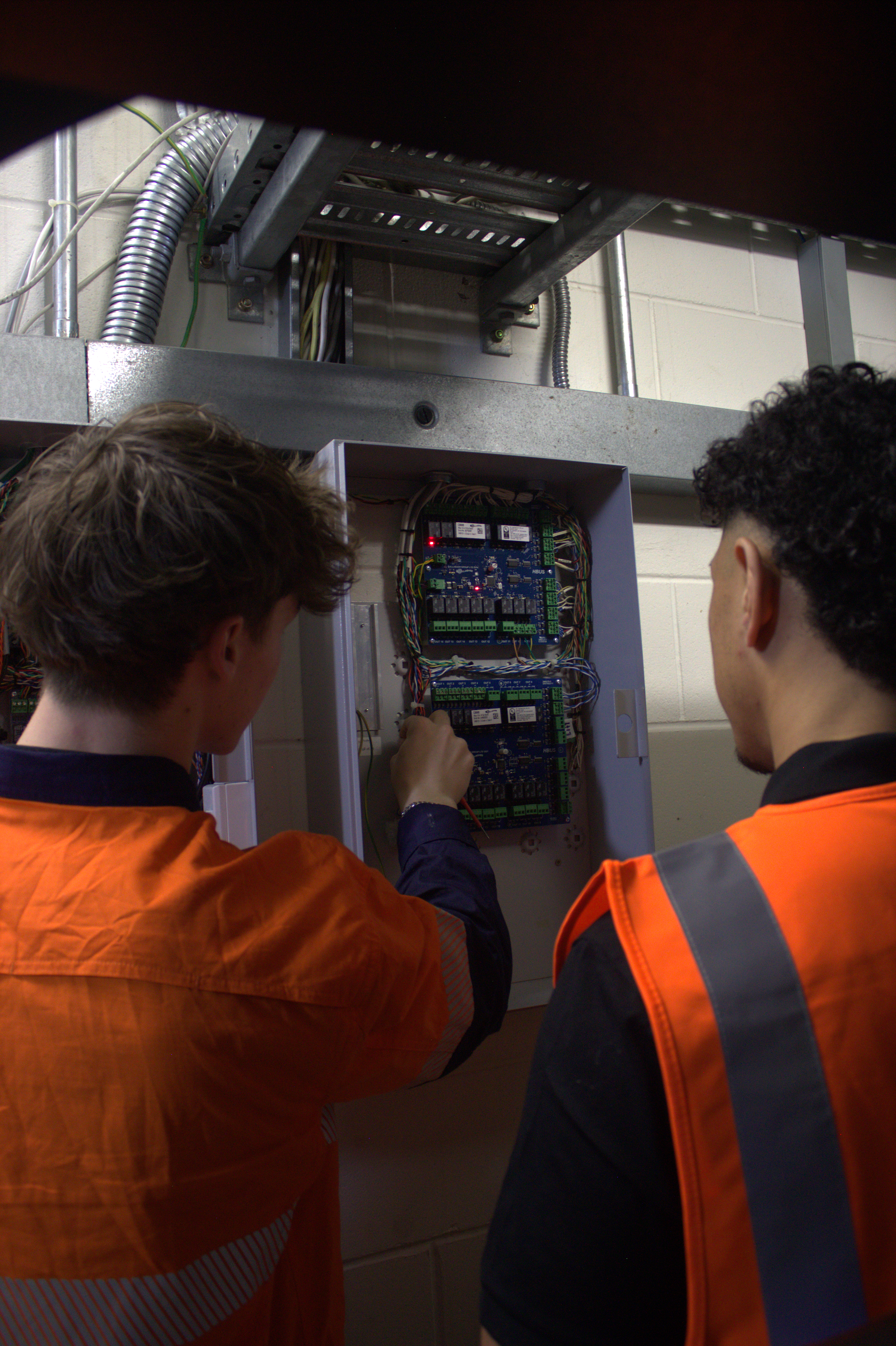 Technicians working on an open alarm and intrusion control panel
