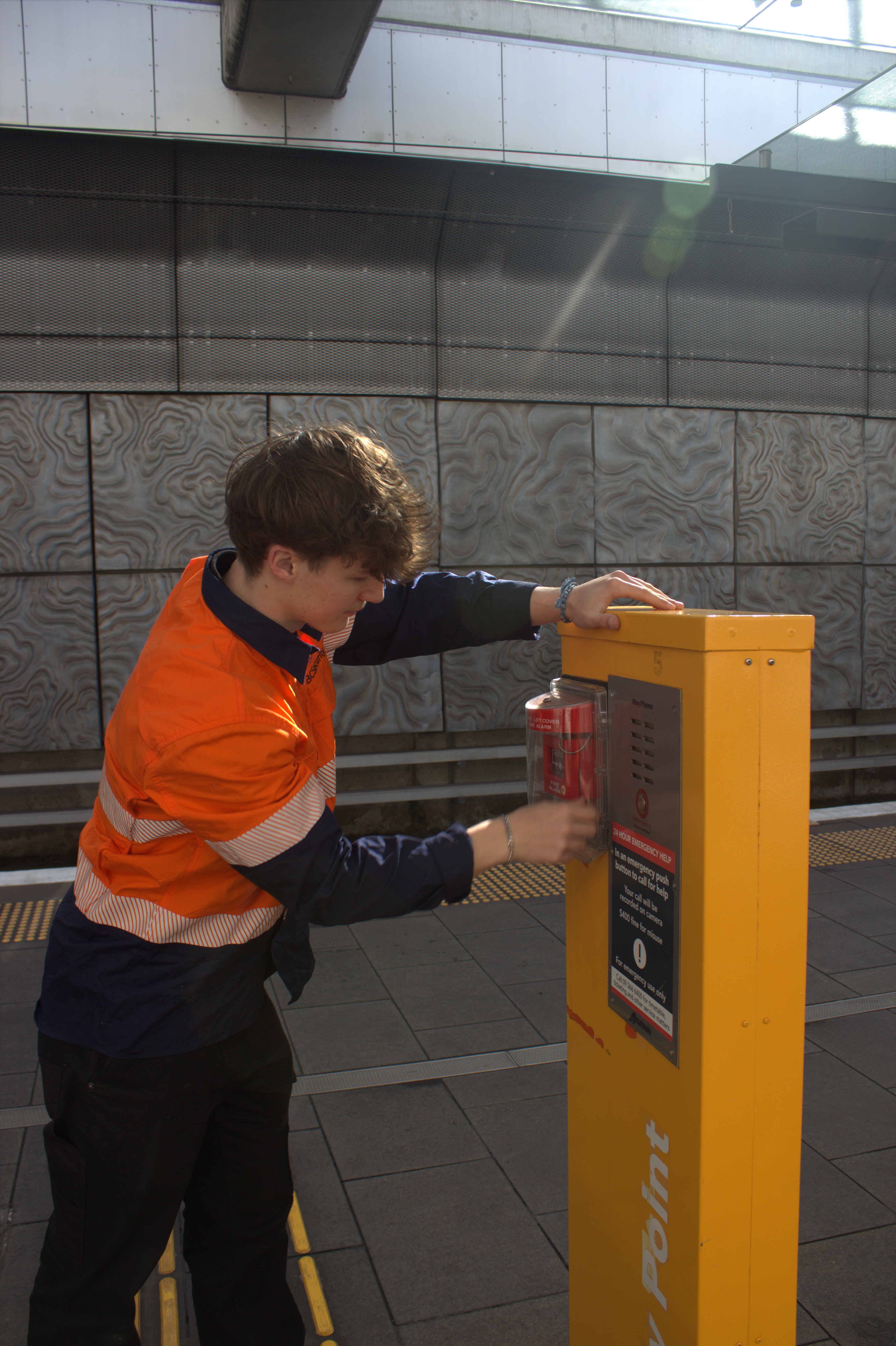 Technician inspecting an emergency help point on a station platform