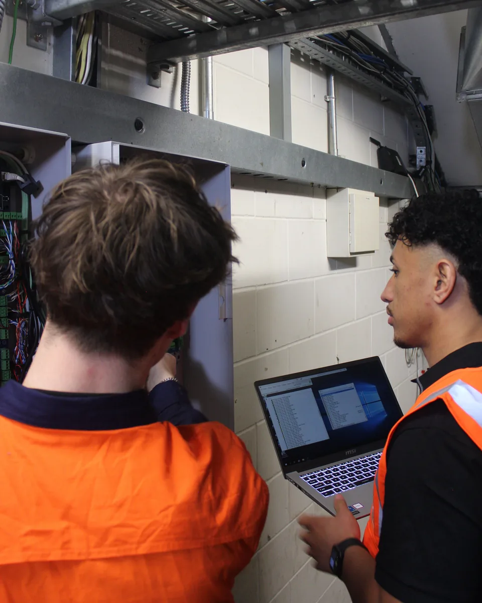 Technicians servicing a panel with diagnostics running on a laptop